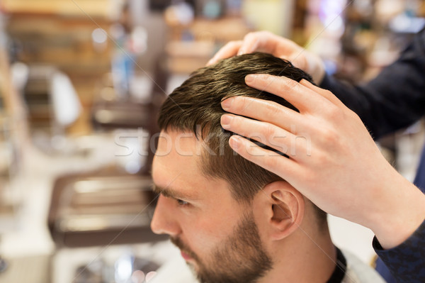 man and barber styling hair at barbershop Stock photo © dolgachov