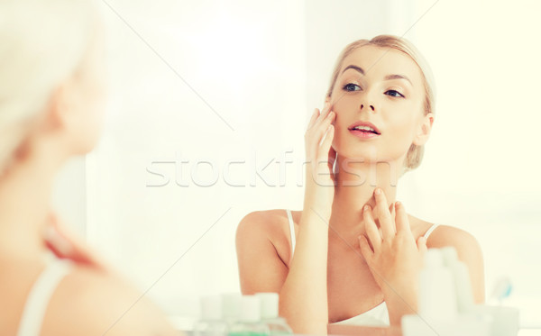 Stock photo: happy young woman looking to mirror at bathroom