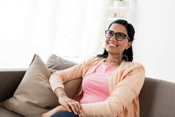 happy smiling young woman sitting on sofa at home Stock photo © dolgachov
