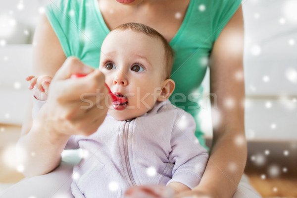 mother with spoon feeding little baby at home Stock photo © dolgachov