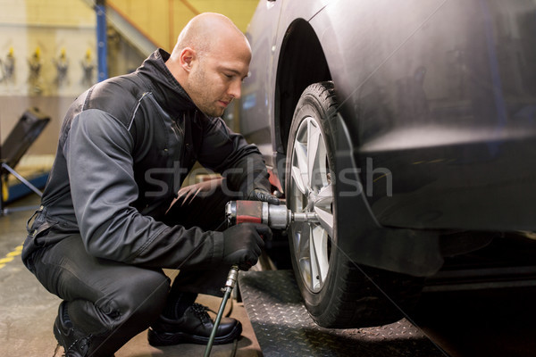 auto mechanic with screwdriver changing car tire Stock photo © dolgachov