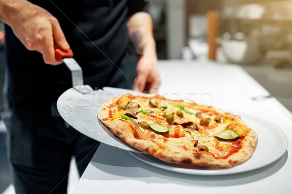 cook with baked pizza on peel at pizzeria Stock photo © dolgachov