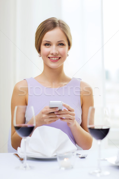 smiling woman with smartphone at resturant Stock photo © dolgachov