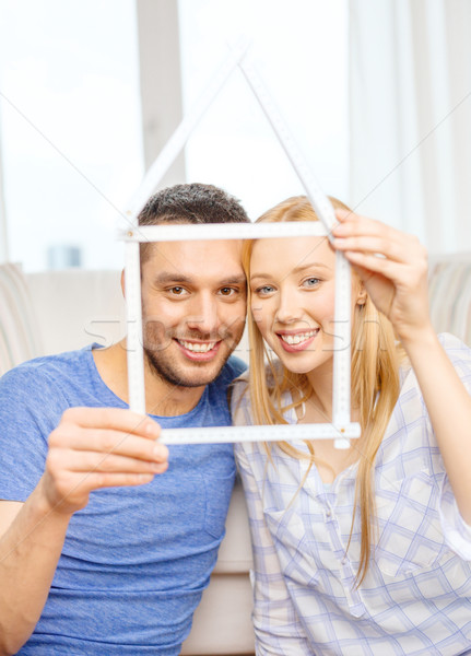 smiling couple with house from measuring tape Stock photo © dolgachov
