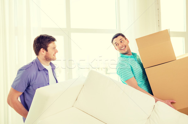 smiling friends with sofa and boxes at new home Stock photo © dolgachov