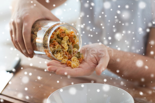 close up of man emptying jar with colorful pasta Stock photo © dolgachov