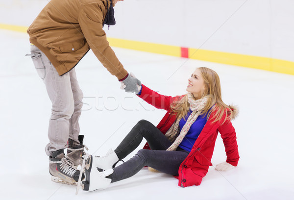 man helping women to rise up on skating rink Stock photo © dolgachov