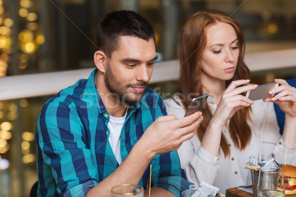 couple with smartphones dining at restaurant Stock photo © dolgachov