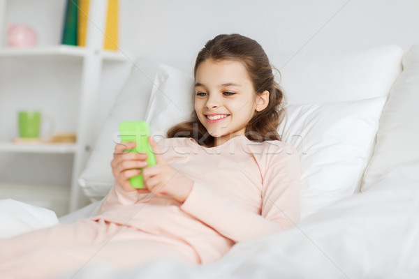 Boldog lány ágy okostelefon otthon emberek gyerekek Stock fotó © dolgachov
