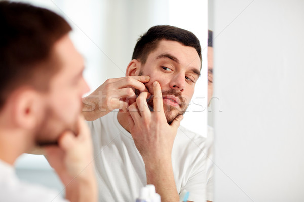 man squeezing pimple at bathroom mirror Stock photo © dolgachov