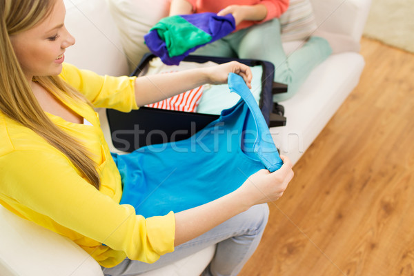 young woman packing clothes into travel bag Stock photo © dolgachov