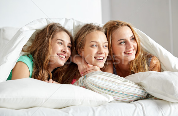Stock photo: happy young women in bed at home pajama party