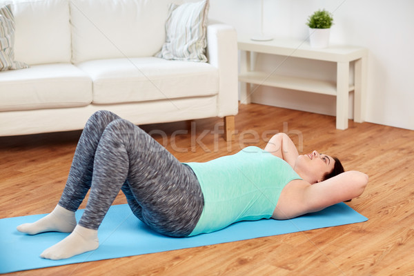 Stock photo: plus size woman exercising on mat at home