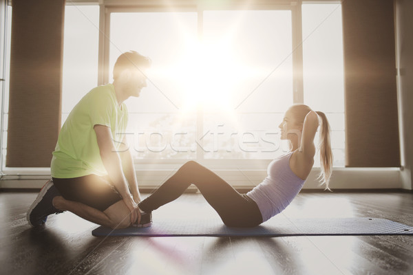 Stock photo: woman with personal trainer doing sit ups in gym