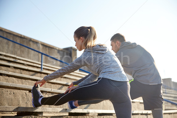 couple stretching leg on stands of stadium Stock photo © dolgachov