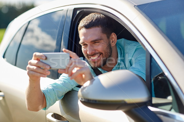 happy smiling man with smartphone driving in car Stock photo © dolgachov