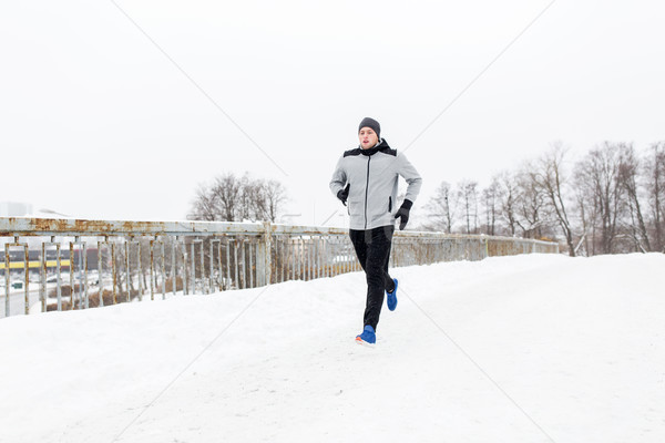 man running along snow covered winter bridge road Stock photo © dolgachov