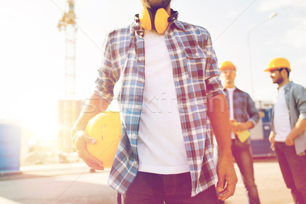Stock photo: close up of builder holding hardhat at building