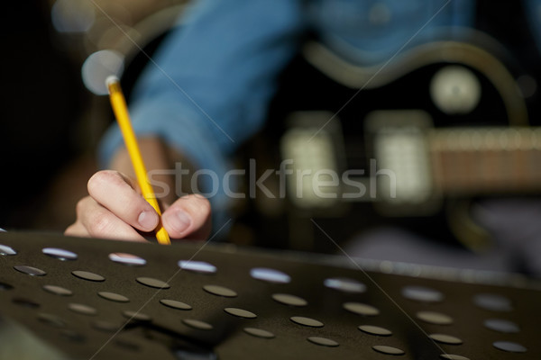 man with guitar writing to music book at studio Stock photo © dolgachov