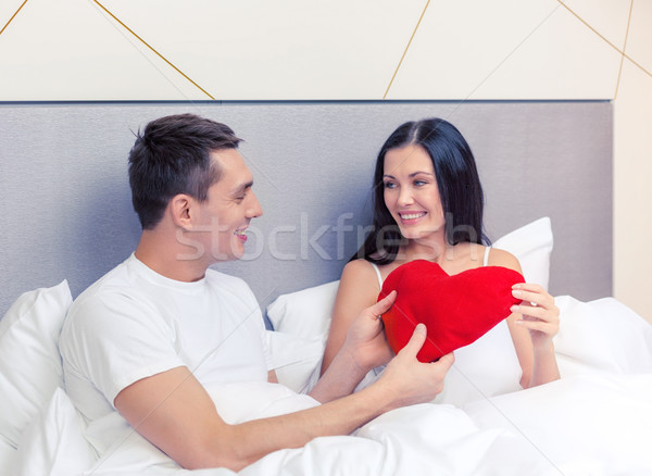 smiling couple in bed with red heart shape pillow Stock photo © dolgachov