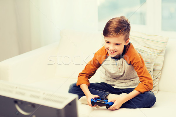 Stock photo: happy boy with joystick playing video game at home