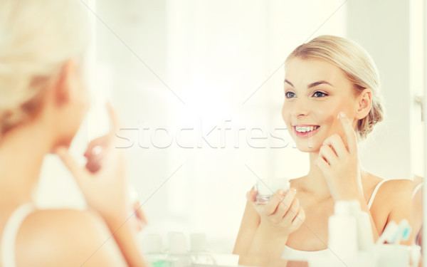 Heureux femme crème visage salle de bain [[stock_photo]] © dolgachov