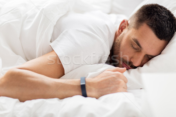 man with smartwatch sleeping in bed Stock photo © dolgachov