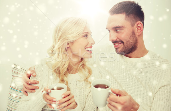 Stock photo: happy couple with cups drinking tea at home