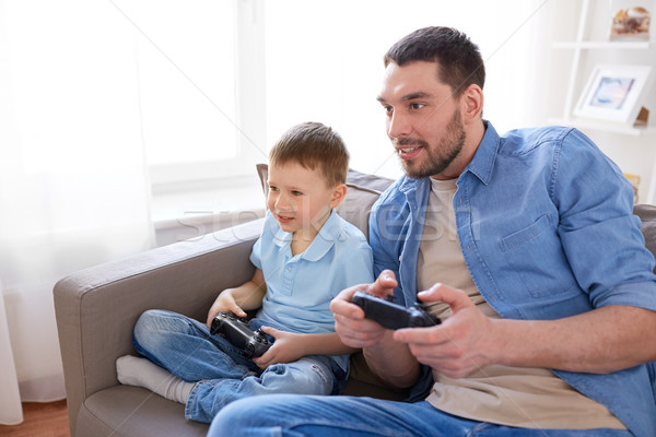 father and son playing video game at home Stock photo © dolgachov