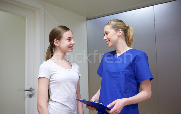 smiling nurse with clipboard and girl at hospital Stock photo © dolgachov