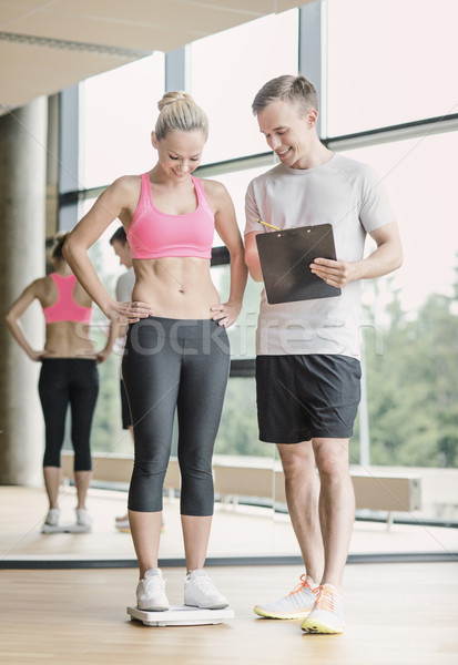 smiling man and woman with scales in gym Stock photo © dolgachov