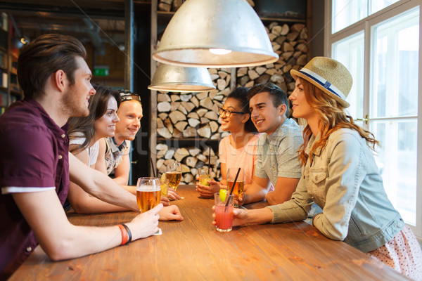 happy friends with drinks talking at bar or pub Stock photo © dolgachov
