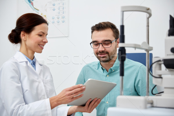 optician with tablet pc and patient at eye clinic Stock photo © dolgachov