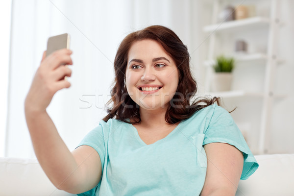 happy plus size woman with smartphone at home Stock photo © dolgachov