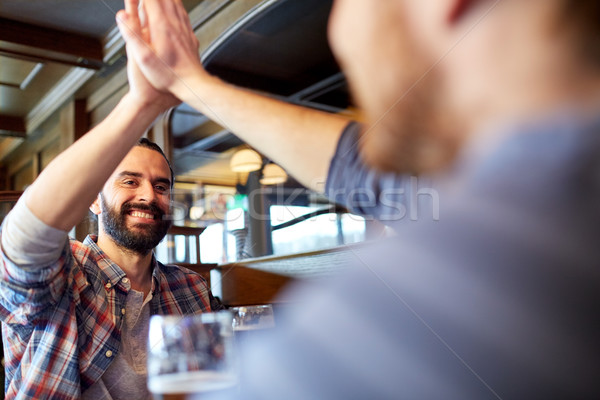 happy male friends making high five at bar or pub Stock photo © dolgachov