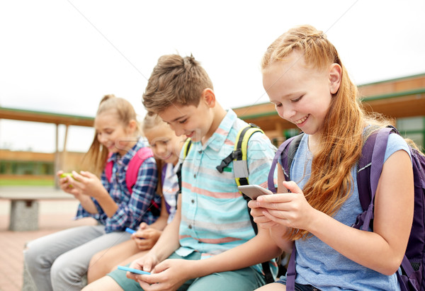 elementary school students with smartphones Stock photo © dolgachov