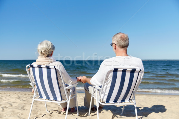 senior couple sitting on chairs at summer beach Stock photo © dolgachov