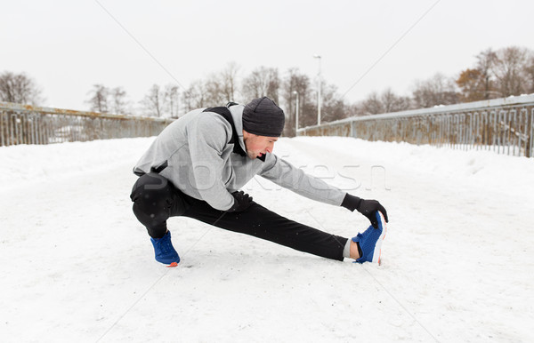 man exercising and stretching leg on winter bridge Stock photo © dolgachov