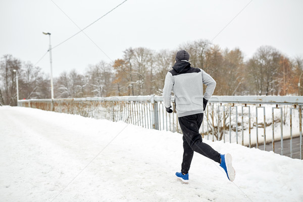 man running along snow covered winter bridge road Stock photo © dolgachov
