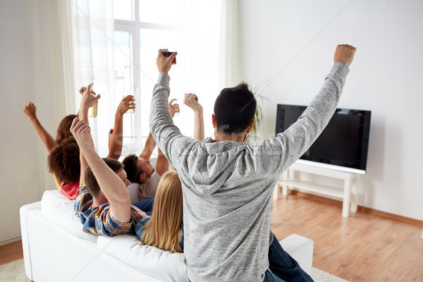 happy friends with beer watching tv at home Stock photo © dolgachov