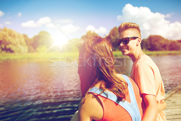 happy teenage couple sitting on river berth Stock photo © dolgachov