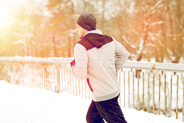 man in earphones running along winter bridge Stock photo © dolgachov