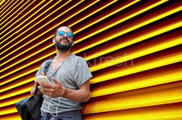 man with earphones and smartphone over wall Stock photo © dolgachov