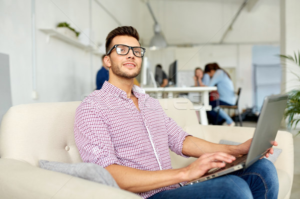 man in eyeglasses with laptop working at office Stock photo © dolgachov