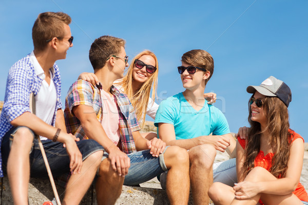 group of smiling friends sitting on city street Stock photo © dolgachov
