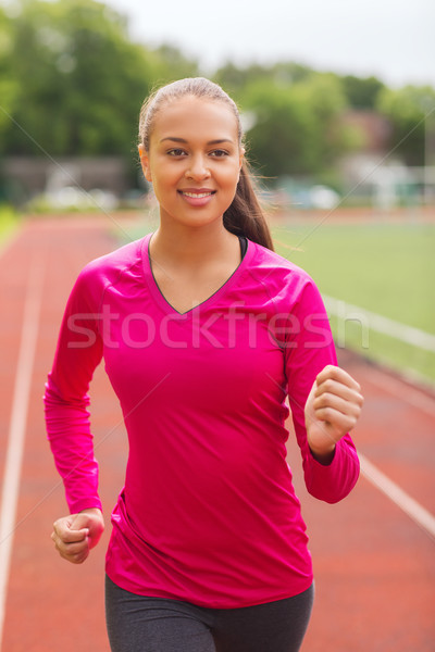 smiling woman running on track outdoors Stock photo © dolgachov