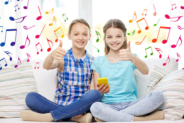 Stock photo: happy girls with smartphone sitting on sofa