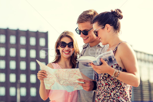 smiling friends with map and city guide outdoors Stock photo © dolgachov