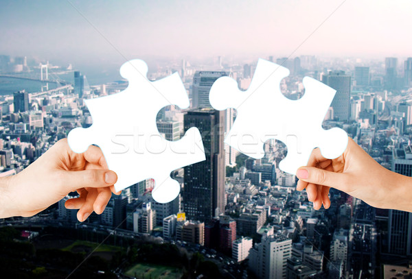 hands with green puzzle over city background Stock photo © dolgachov