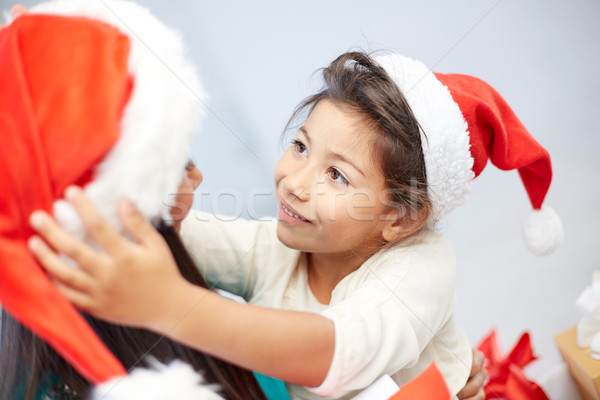 happy mother and little girl in santa hats at home Stock photo © dolgachov